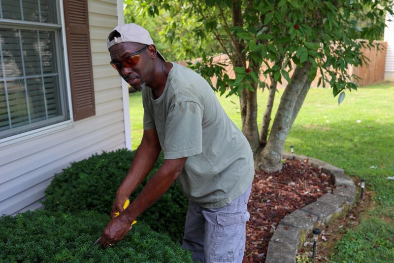A portrait of a black man trimming the hedge