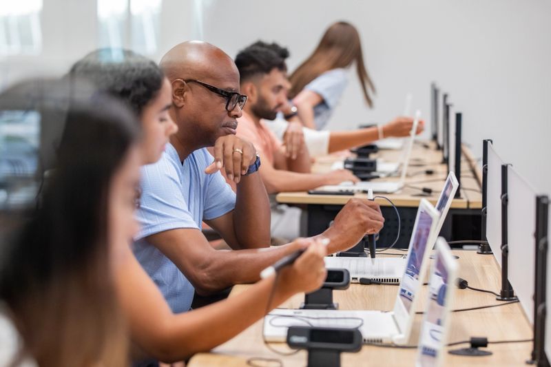 A mix of people are attending a class together in a computer lab.
