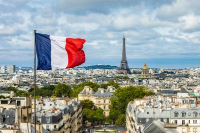 French flag over Paris with Eiffel Tower in background.