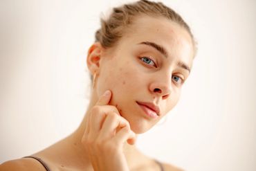 Close-up of a woman touching her cheek with a calm expression.