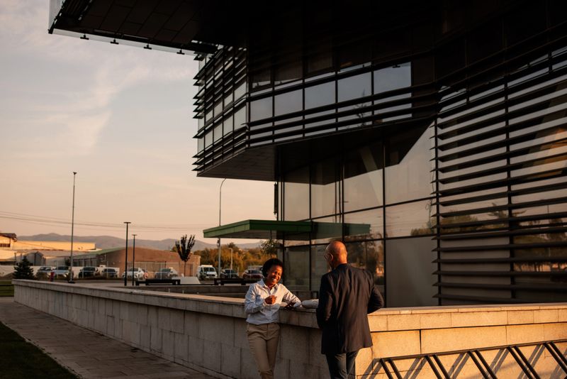Two people talking business outdoors in a business area ,with the office building in the background