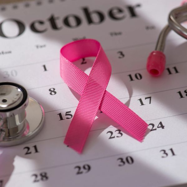 Pink breast cancer ribbon on October calendar with stethoscope.