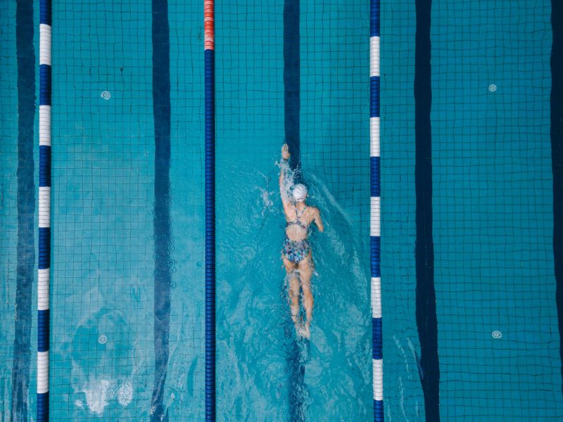 Drone point of view on swimming pool Asian Chinese Professional female swimmer freestyle swimming the front crawl stroke