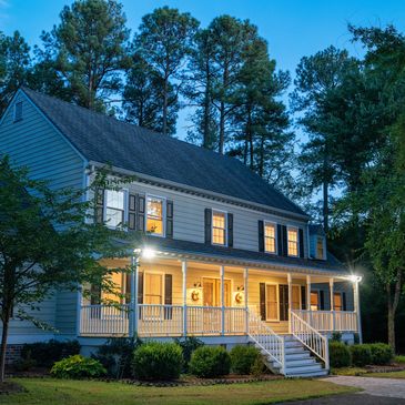 A cozy two-story house with warm lights on a quiet evening.