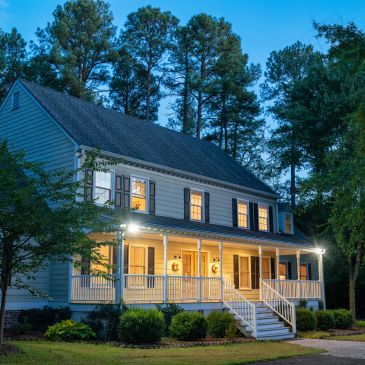 A cozy two-story house with lights on during twilight.