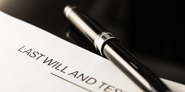 A pen resting on a last will and testament document.