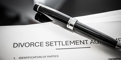 A pen resting on a divorce settlement agreement.