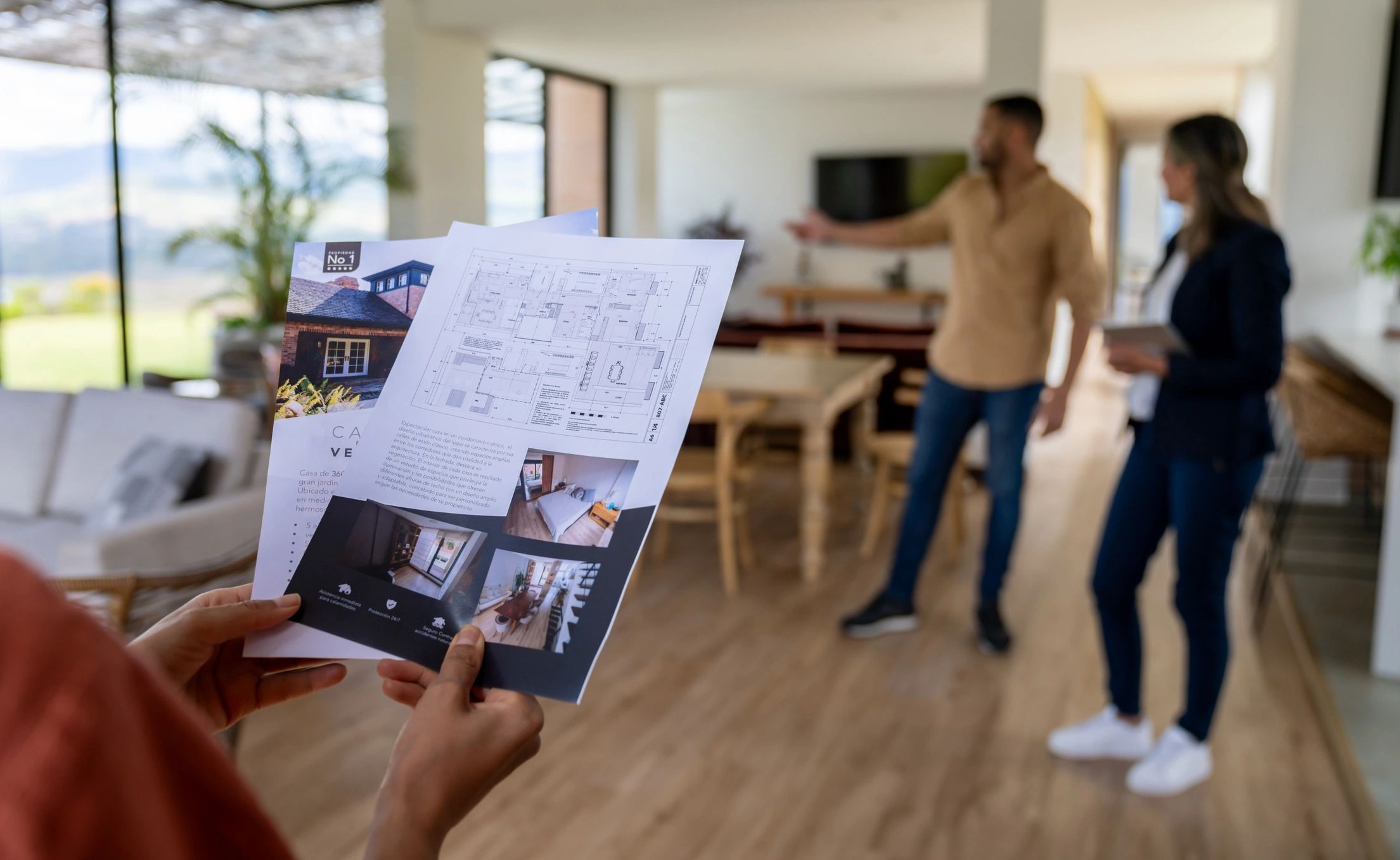Real estate agent showing property plans to clients indoors.