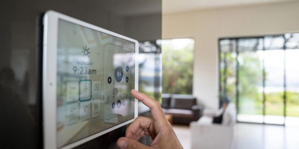 Hand adjusting smart home control panel in a modern living room.