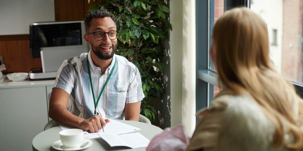 Two people having a meeting at a small round table. 