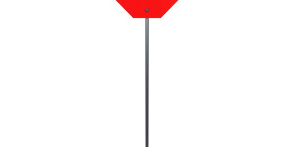 A blank red octagonal stop sign on a black pole with a white background.