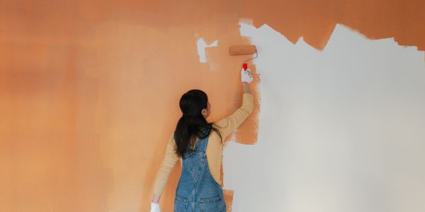 Mujer pintando una pared de naranja.