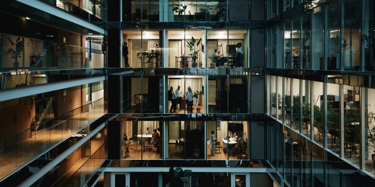 People working and conversing in a modern office building at night.