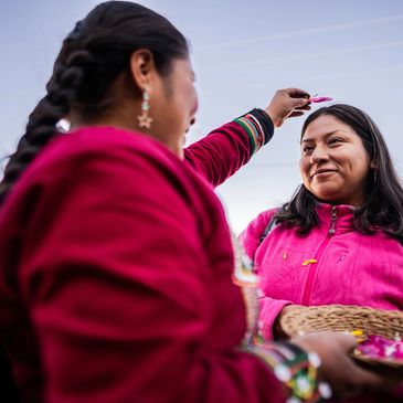 Two women in traditional clothing exchange a playful moment.