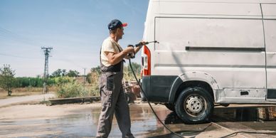 Man pressure washing a brick wall outside a house patio.