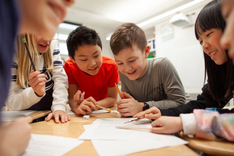 Group of multiracial elementary school students talk and enjoy studying together in a classroom