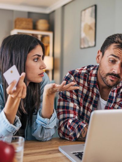 Pareja discutiendo sobre finanzas con computadora y tarjeta.