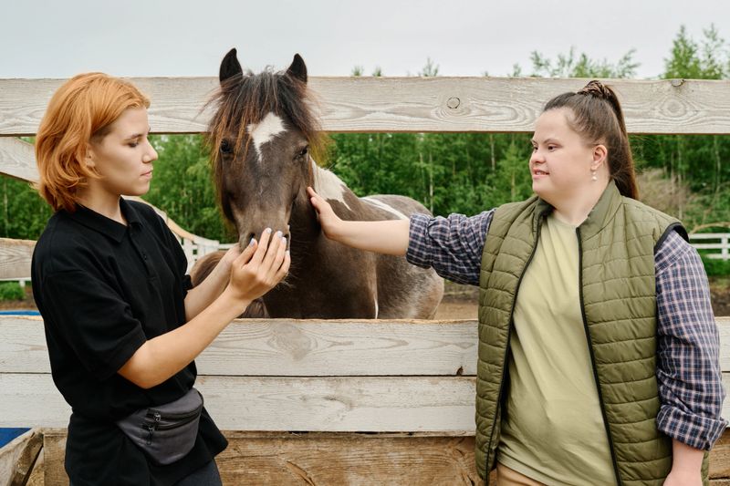 Young people engaging with beautiful horse on outdoor ranch, both smiling while enjoying the moment and strengthening bond with animal