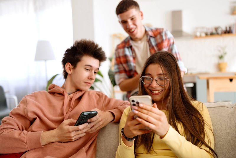 Group of smiling teenagers surfing the net from home