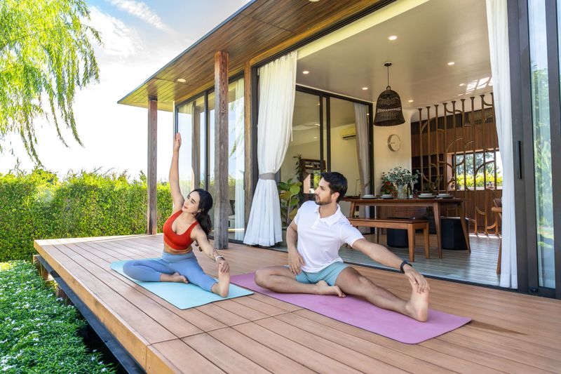 A Latin American man and woman are seated on yoga mats outdoors for practicing yoga session in the morning at home enhancing the sense of mindfulness and relaxation in the moment including flexibility.