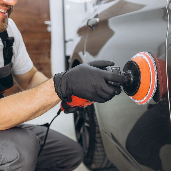 Person polishing a car with a buffer.