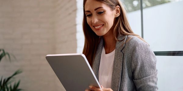 Smiling woman using a tablet in a modern office setting.