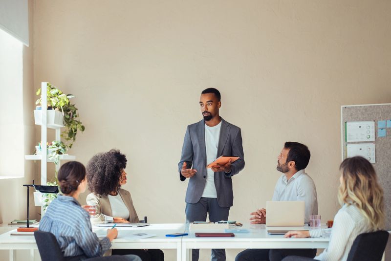 A diverse group of business people engaging in a business meeting, exchanging ideas and collaborating on a project in a modern office setting.