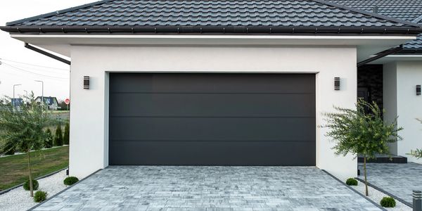 Modern house with a sleek black garage door and tiled driveway.