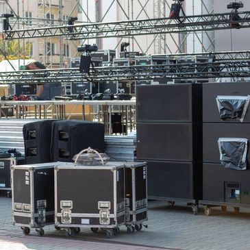 Outdoor stage setup with speakers and equipment cases.