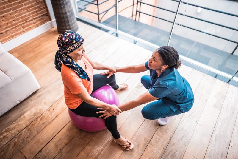 Physiotherapist doing exercise with patient at home - woman battling cancer