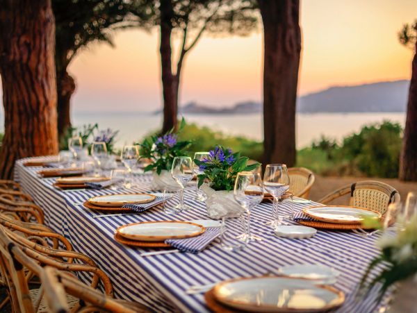 Elegant outdoor dining table set by the sea at sunset.