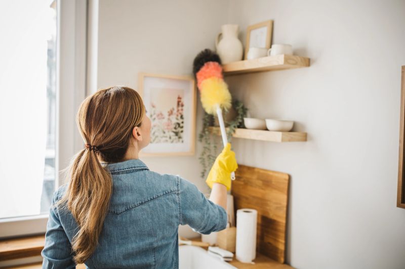 Young woman dusting a surface at home kitchen.