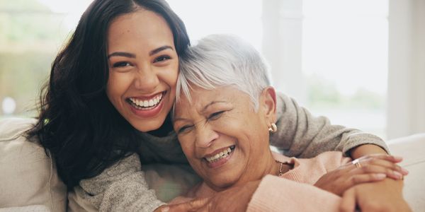 A joyful young woman embracing an older woman, both smiling warmly.