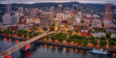 Aerial view of a city skyline with a bridge over a river at dusk.