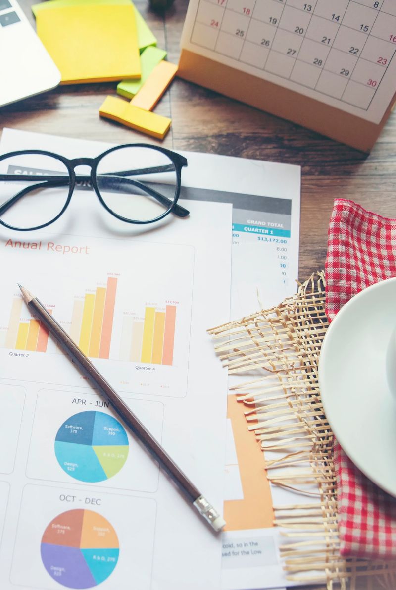 Business computer office wooden desk with annual report, summary report, document, paper, calculator, cup of coffee, and working space. Business executive office desk concept-vertical image.