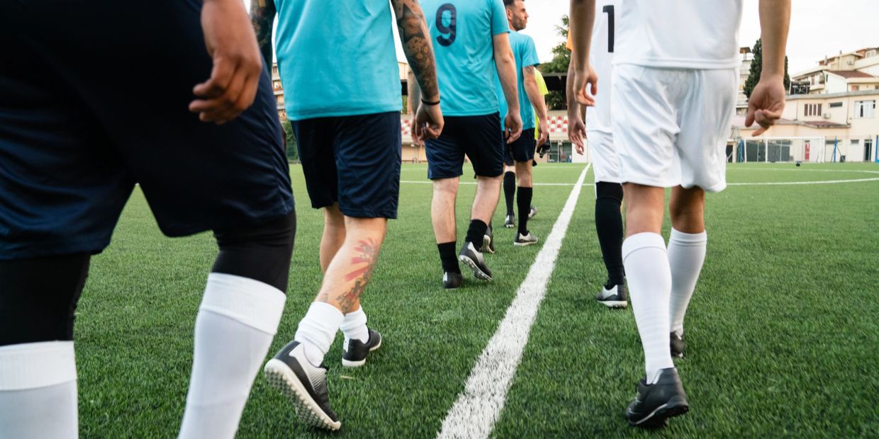 Soccer players walking on the field in blue and white uniforms.