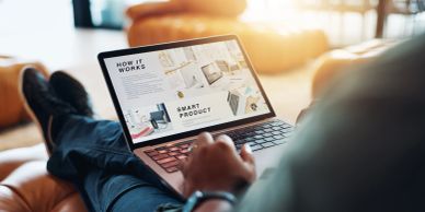 Person relaxing and browsing a smart product website on a laptop.