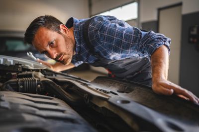 Man inspecting car engine under the hood.