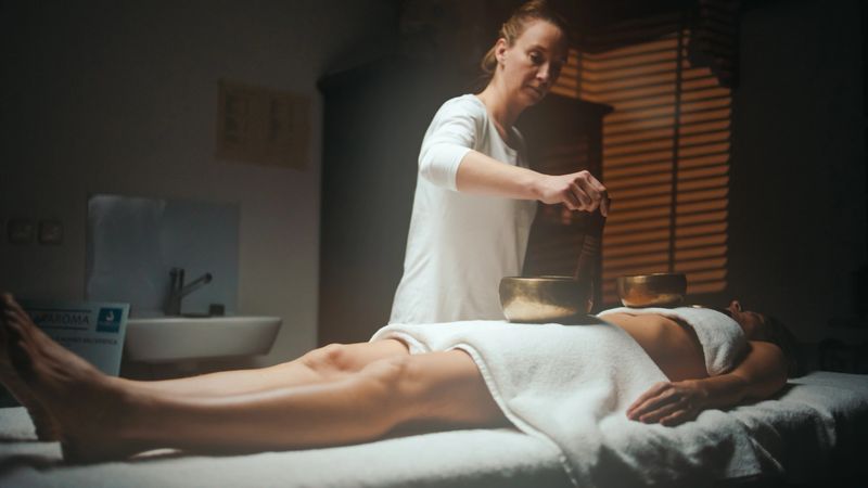 A professional therapist applies treatment to a relaxed client in a serene spa setting, using massage tools to enhance wellness.