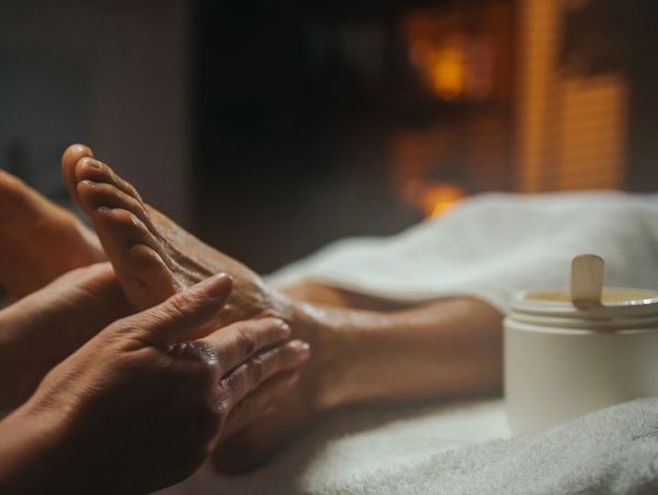 A person receiving a relaxing foot massage with cream nearby.