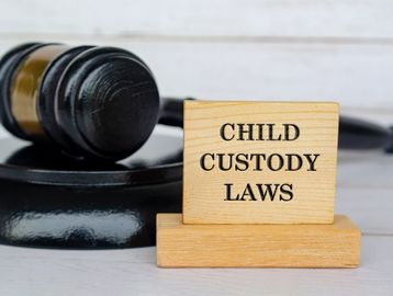 Wooden blocks reading "Child Custody Laws" with a judge's gavel.