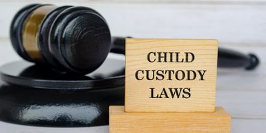 Wooden block with 'Child Custody Laws' text beside a judge's gavel.