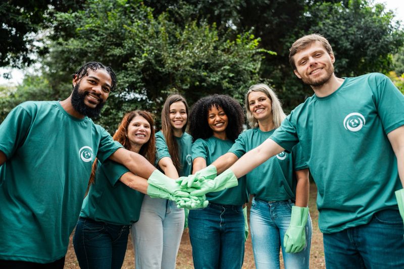 Portrait of a group of volunteers with hands stacked at public park