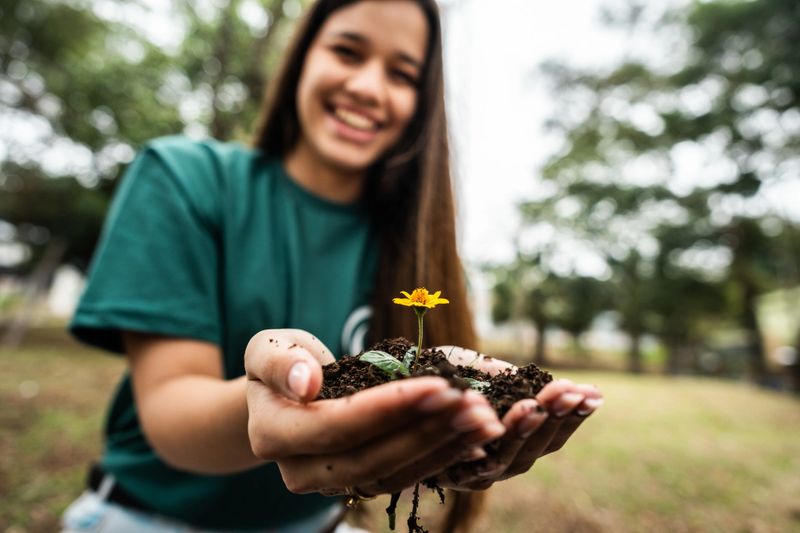 Close-up of a woman holding sprout young plant outdoors