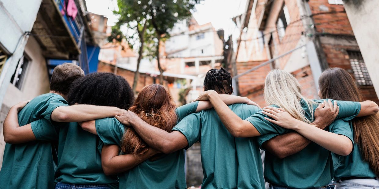 Group of diverse people with arms around each other, showing unity.