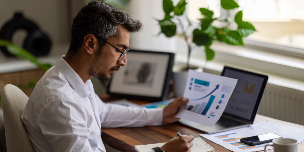 Man analyzing charts at his desk.