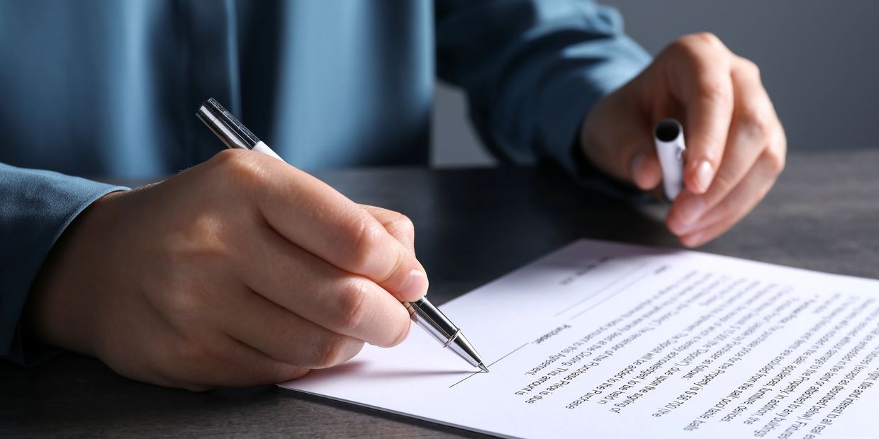 Person signing a contract at their business lawyer's office.