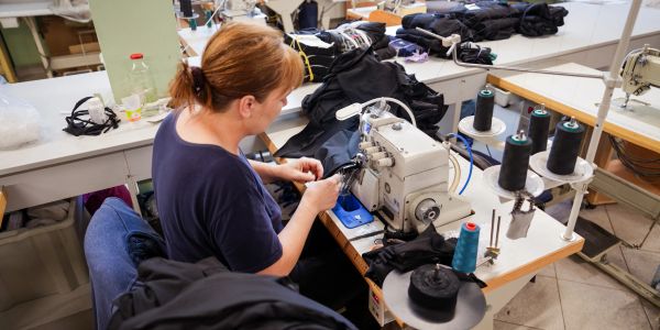 Woman sewing fabric on industrial sewing machine.