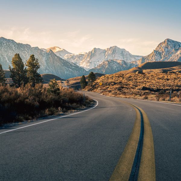 Curvy mountain road with snowy peaks in the background.