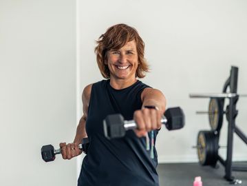 Smiling woman lifting dumbbells during workout.